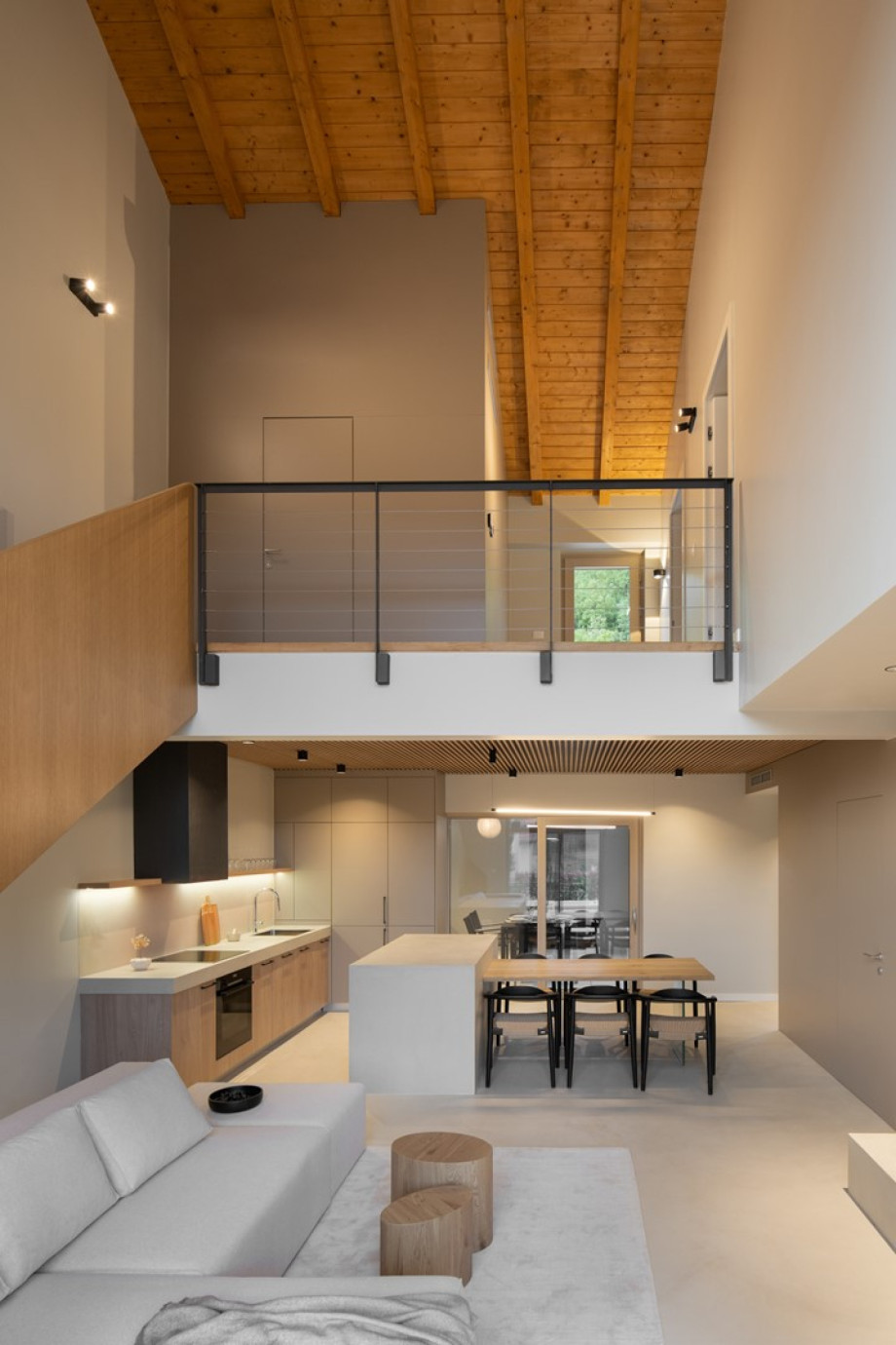 View of the open-plan living area and kitchen, featuring high ceilings and stairs to the upper level.