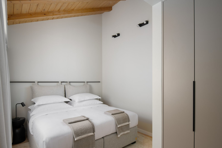 A bedroom under a traditional wooden ceiling, featuring high-quality furnishings and a large wardrobe.