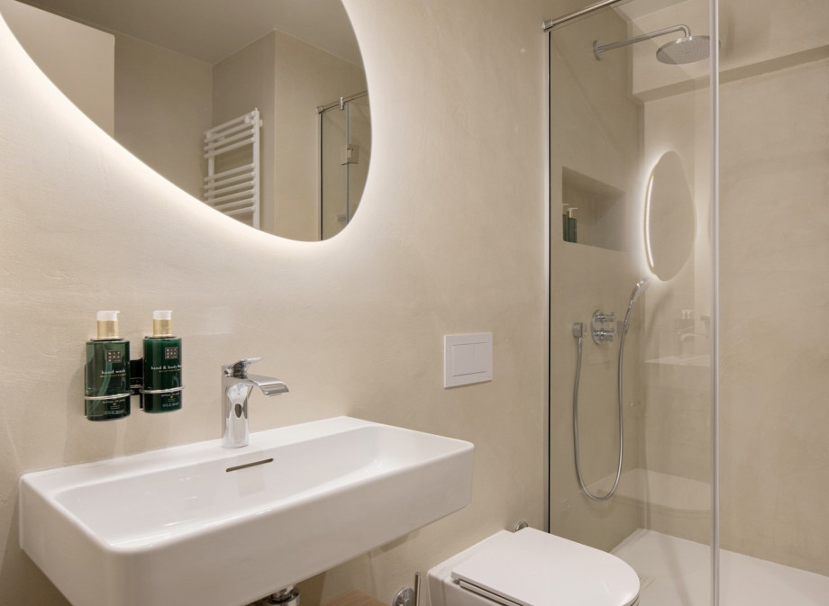 This contemporary bathroom features a clean, minimalist aesthetic with stone-textured walls and a rainfall shower.