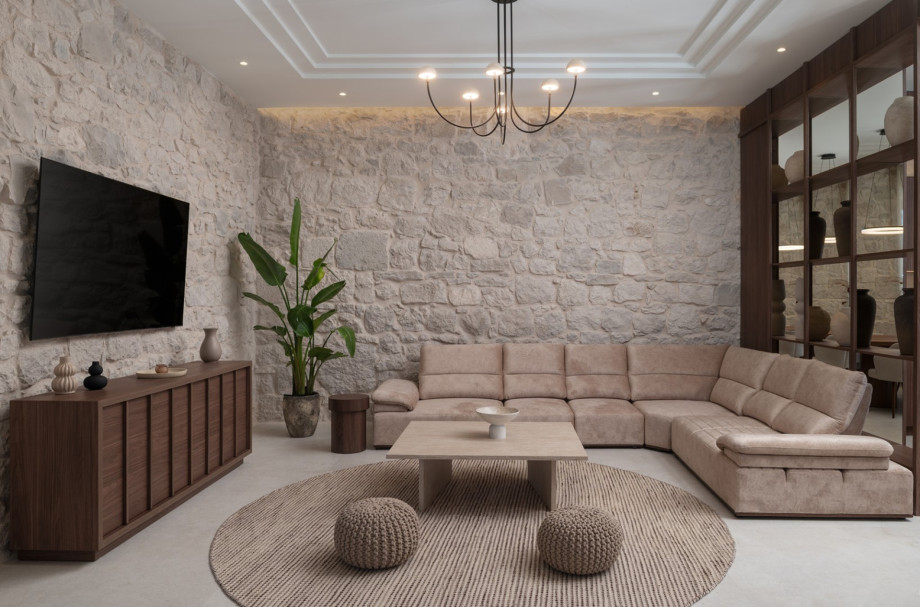 One of three living areas features natural stone walls, a large sofa, and a flat-screen TV.