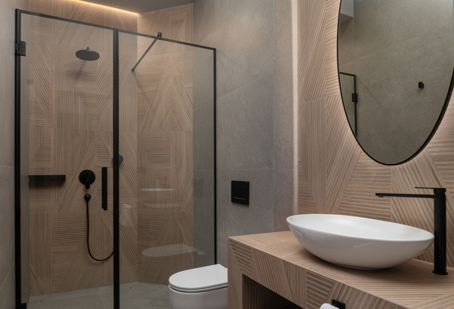 This en-suite bathroom features stylish wood-patterned tiles and a sleek black shower frame.