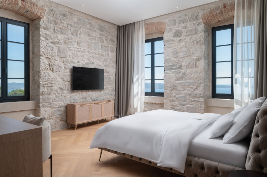This en-suite bedroom combines traditional stone walls with elegant Mediterranean decor.