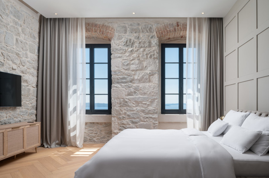 High-end interiors feature a flat-screen TV against a natural stone wall.