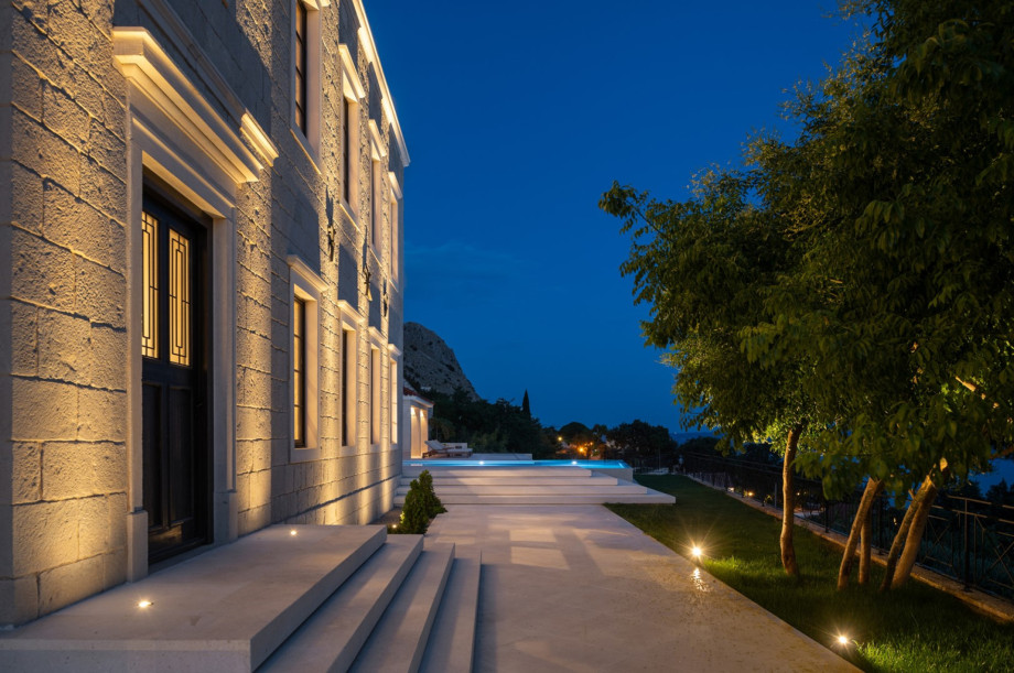The traditional stone exterior is beautifully illuminated, highlighting the classic Mediterranean style.