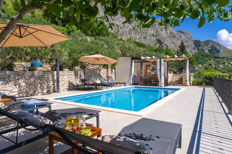 Pool area surrounded by nature, offering stunning mountain and a sea view.