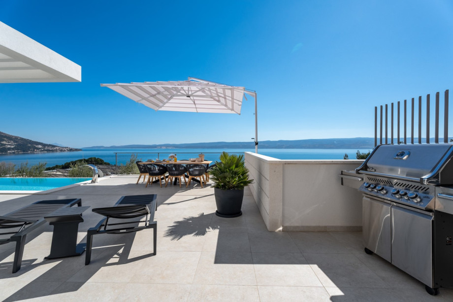 Outdoor dining area with a Napoleon gas Grill with a kitchen worktop with a sink next to it.