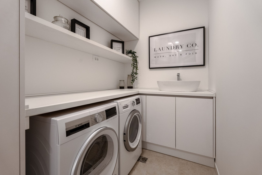Nicely decorated Laundry with a washing machine, a dryer, and ironing amenities.