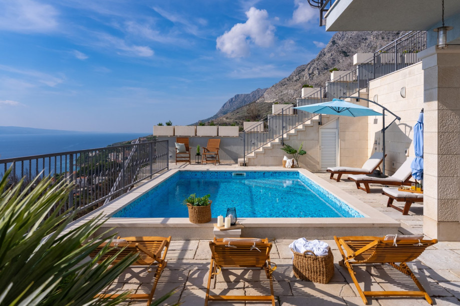 The modern pool with crystal-clear water is nestled against the steep slope, offering a blend of luxury and mountain nature.
