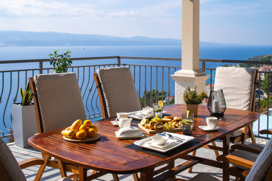 The spacious balcony with an outdoor dining table provides a perfect setting for meals with stunning sea views.