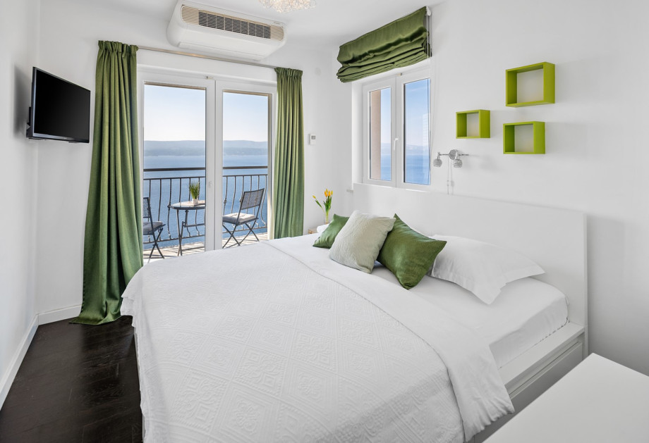 Bedroom No. 2, styled with refreshing green accents, features a modern white queen-size bed, a TV, air conditioning