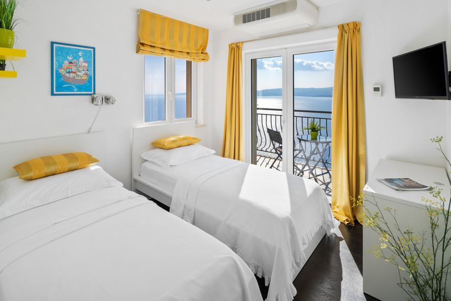Twin Bedroom No.3, highlighted by sunny yellow details, provides ample light and is equipped with 2 single beds (90x200), TV, and A/C
