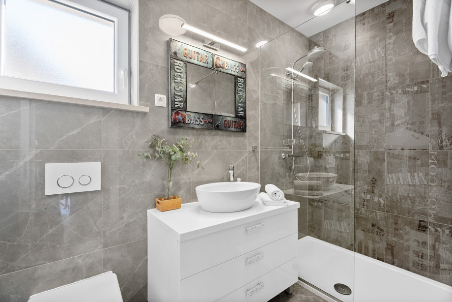 A family bathroom features a shower for bedrooms No. 2 and No. 3. Each bathroom is equipped with toiletries such as shampoo, conditioner, shower gel, bathrobes, slippers, and a hairdryer