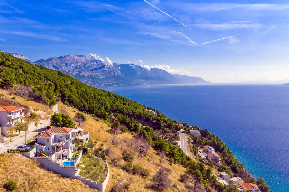 A spectacular aerial shot highlights the villa's privileged position on the hillside, overlooking the vast blue Adriatic