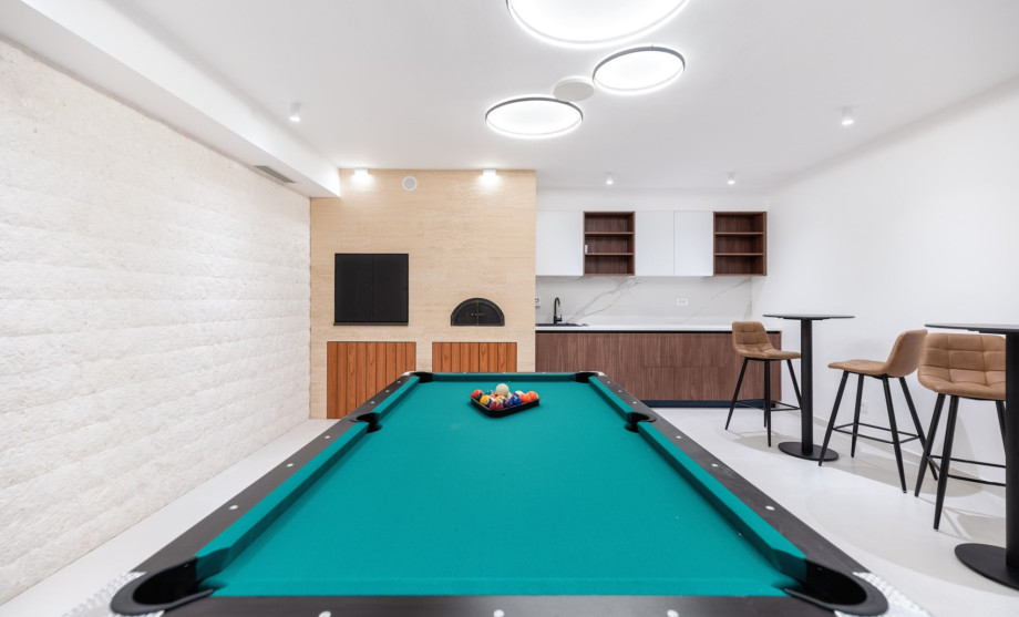 Next to it is a fun zone with a Pool table (Billiards), a TV, two bar tables, a kitchenette, and a barbecue area