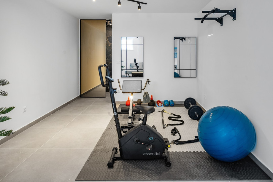 Ein kleiner Fitnessraum mit Geräten wie einem Heimtrainer und einem Pilatesball