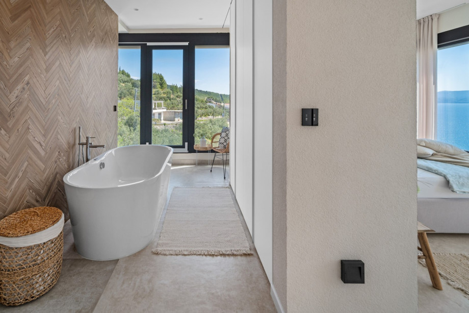 The bathroom features a walk-in shower, sink, toilet, and a luxurious self-standing bathtub.