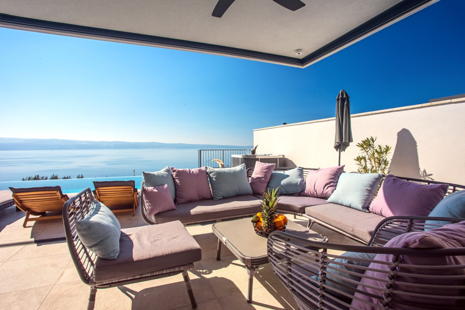 Covered lounge area next to pool and outdoor dining area