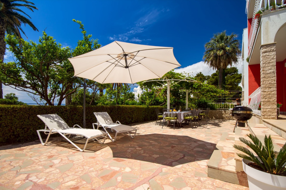 Outdoor dining area with a barbeque in front of the living room and kitchen