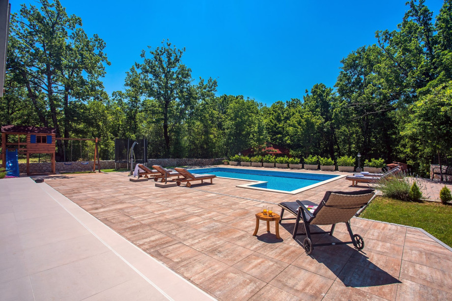 A place for the kids with trampoline, swing and a wooden playhouse with a slide
