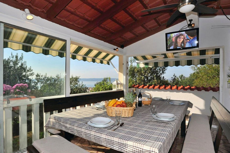 Covered dining area for 14 people with a TV, barbecue and summer kitchen