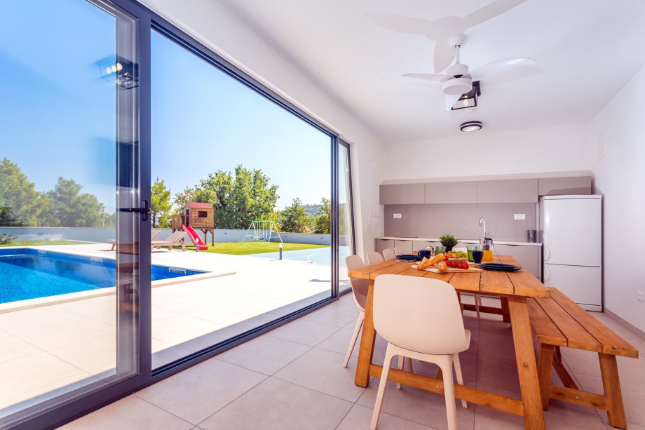 A fully equipped summer kitchen with TV, fridge, barbecue and dining area for 10 pax