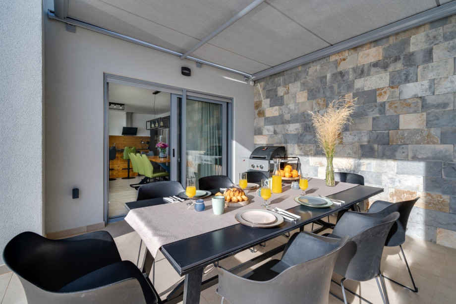 A covered outdoor dining area with a barbecue (direct approach to the kitchen and living room)