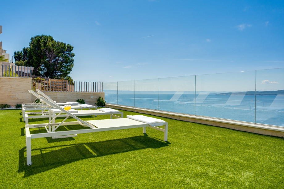 The artificial grassplot a few steps lower of the pool (also approachable from the wellness zone at the lower ground floor)