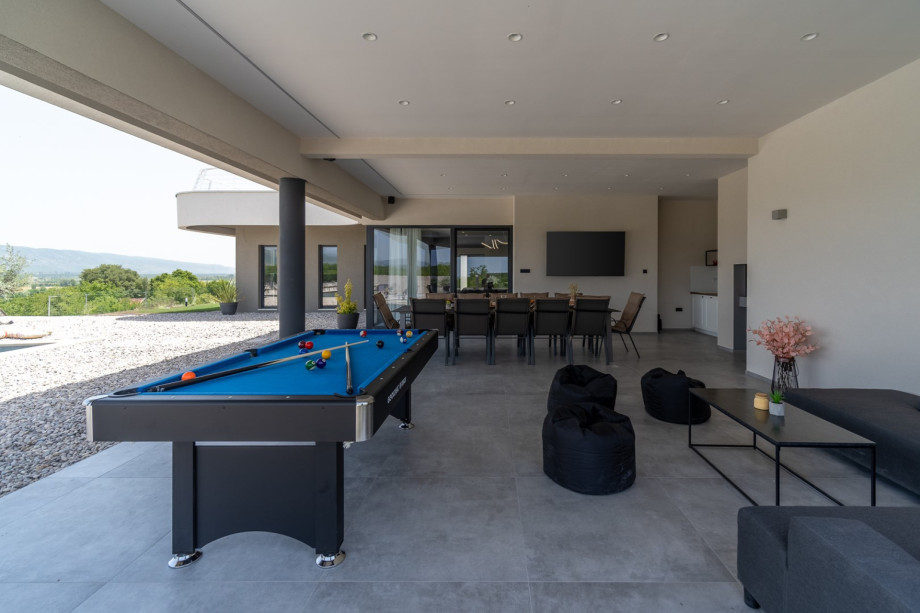 Covered area (77sqm) with an outdoor kitchen, a traditional barbecue (woods and charcoal), a huge flat screen TV with surround speakers, a dining table for 12 people