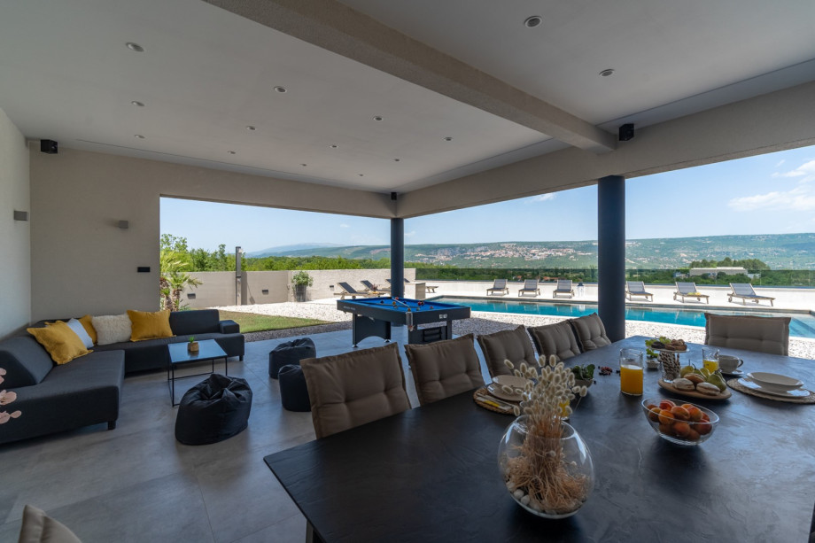 Covered area (77sqm) with an outdoor kitchen, a traditional barbecue (woods and charcoal), a huge flat screen TV with surround speakers, a dining table for 12 people