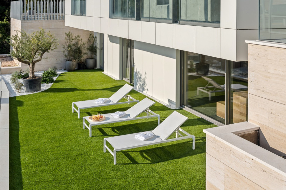 The artificial grassplot a few steps lower than pool level (also approachable from the wellness zone at the lower ground floor)