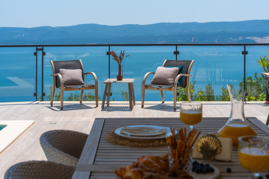 Relaxing by the pool with a view of the ocean and outdoor furniture.
