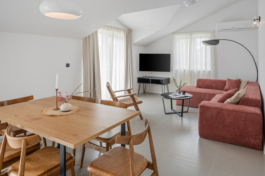 Chic and comfortable living area with a TV, a sofa, and a terrace with an outdoor table