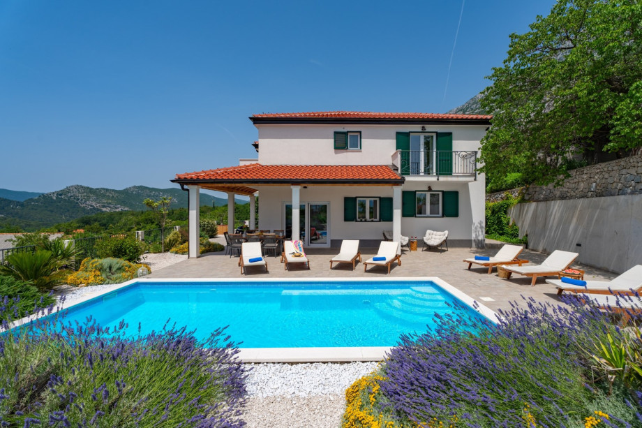 Outdoor dining area with a BBQ and a pool view