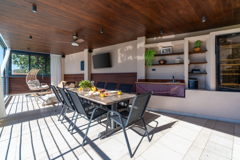 The outdoors offers a covered dining area, TV and summer kitchen with a fridge and ice maker