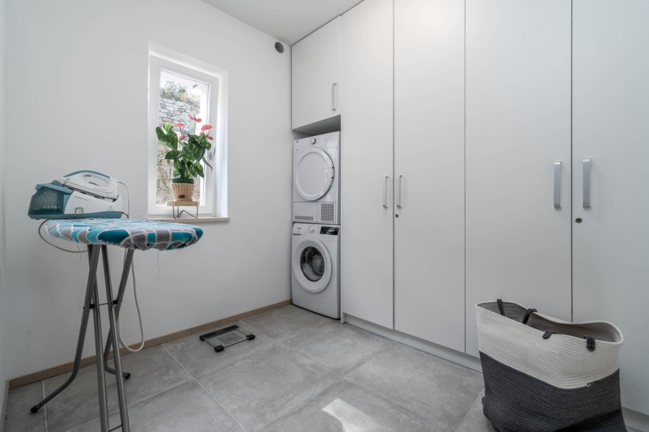 Laundry room on the ground floor with a washing machine, a dryer, and a steam iron station.