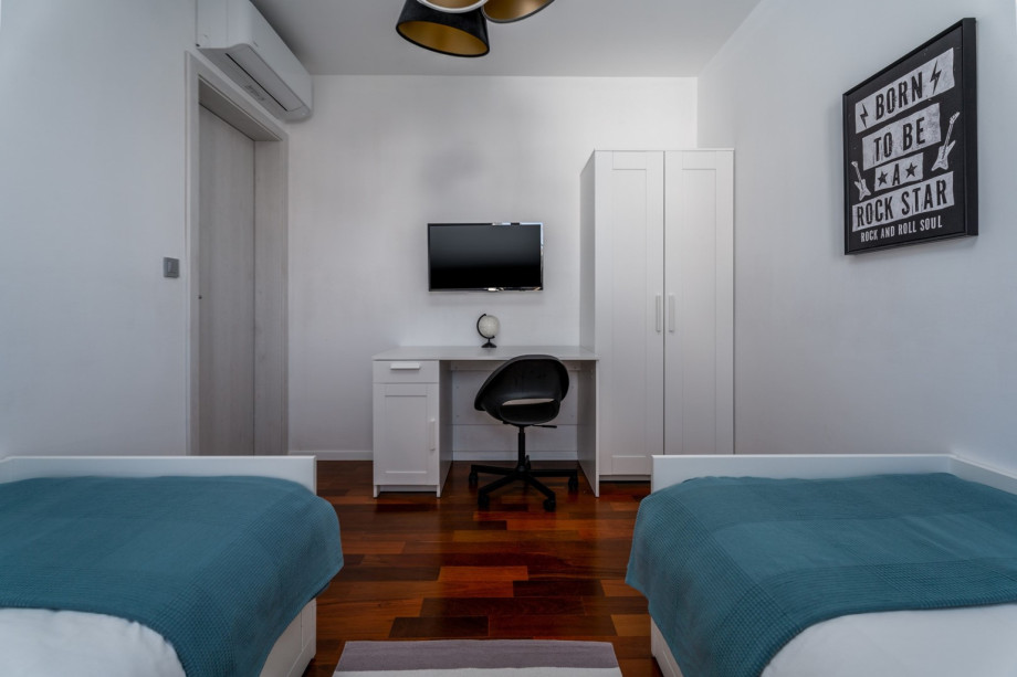 Bedroom No3 with air-conditioning, a TV, and views on the garden and the neighborhood.