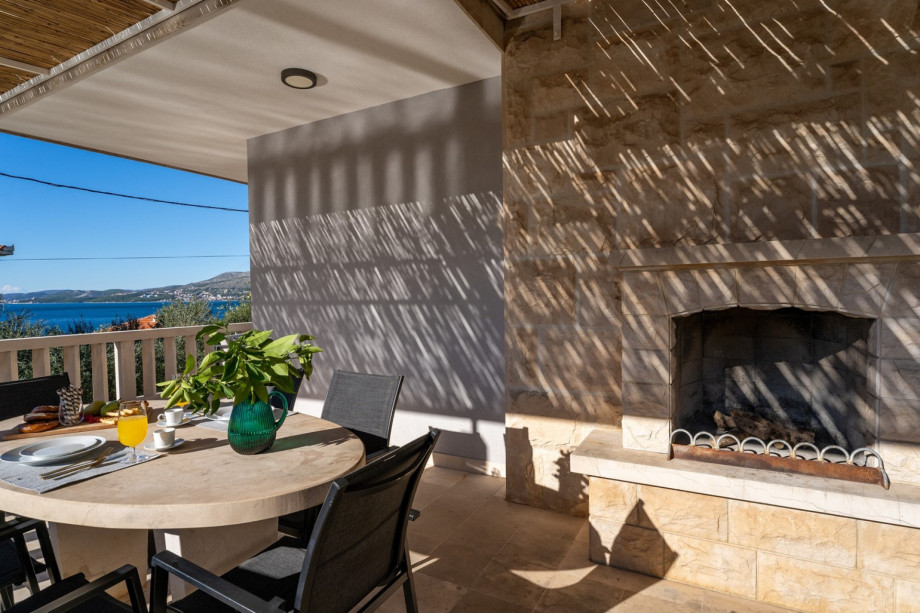 A outdoor dining area with a fireplace and a terrace with sea view.
