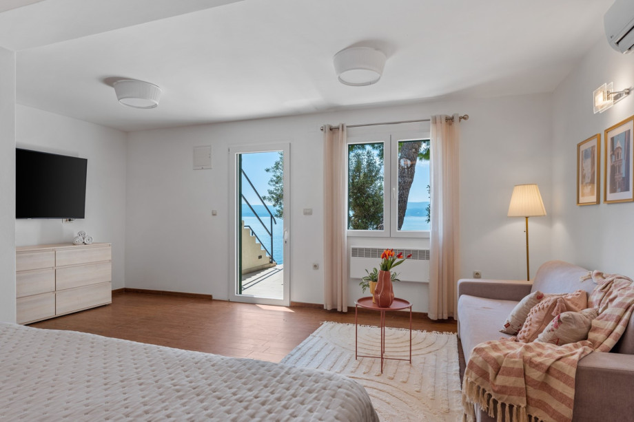 The bedroom area offers the views on the sea and the grassplot with a pine tree.