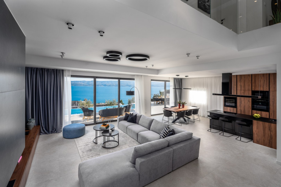 A spacious dining area, and a living room with a flat-screen TV and overviewing of the sea and pool area.