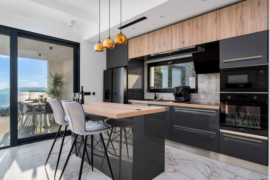 The living area is connected by an outdoor dining area and the pool area by glass floor-to-ceiling doors.