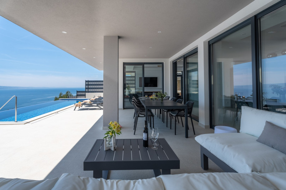 A covered dining area for 10 people with a barbecue (woods, charcoal) next to it