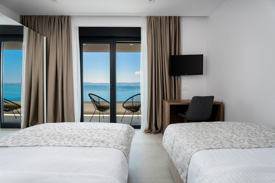 Bedroom with an A/C, a TV, and balcony with sea views and outdoor furniture.