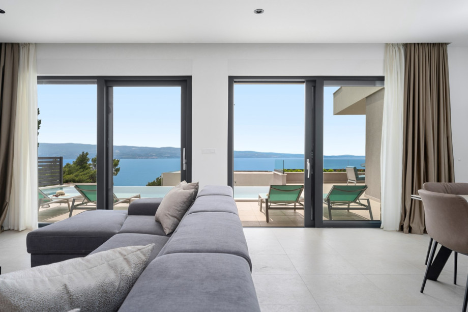 A spacious dining area, and a living room with a flat-screen TV and overviewing of the sea and pool area.