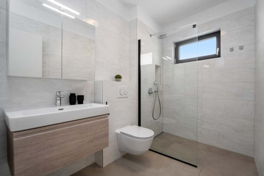 The family bathroom with a shower,  and there is a laundry room with a washing machine and a dryer