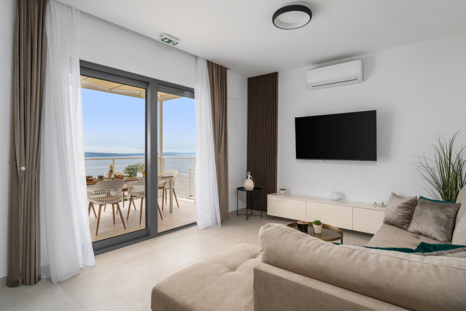 A spacious dining area, and a living room with a flat-screen TV and overviewing of the sea and pool area.