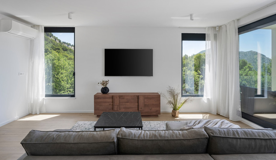 Living room with a TV, air conditioning, and sliding doors that lead to the outdoor dining area