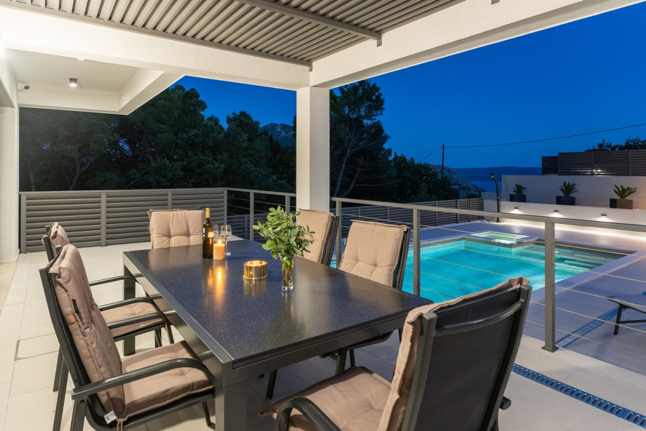 The outdoor area offers a covered dining area and a traditional barbecue