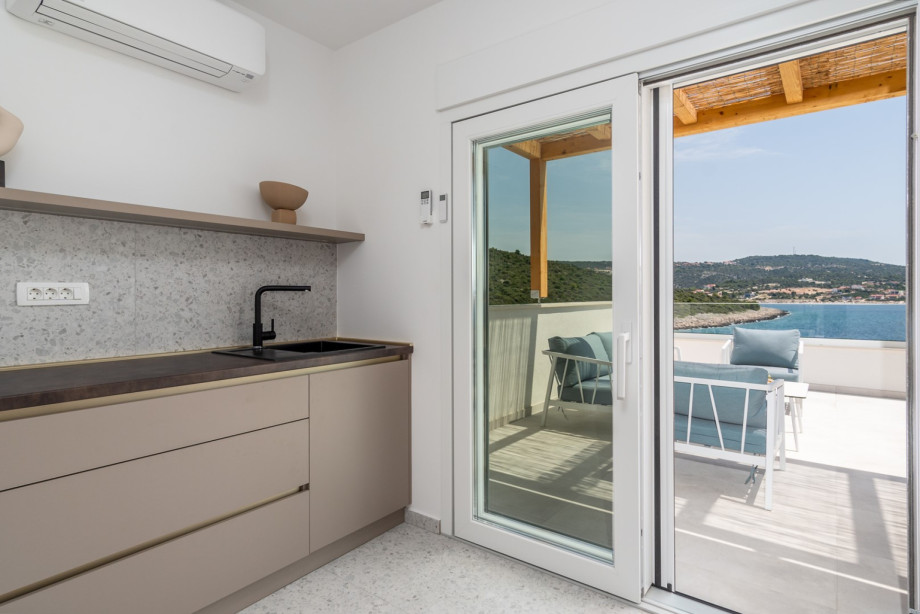 kitchenette with a small fridge, a sink and some dishes. Next to it there is a washing machine, a dryer and ironing amenities.