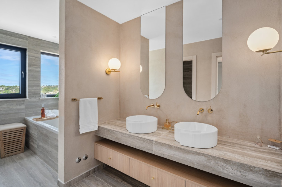 An en-suite bathroom with a bathtub and a shower, a double sink, and a toilet