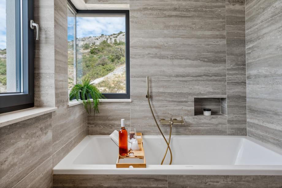 An en-suite bathroom with a bathtub and a shower, a double sink, and a toilet